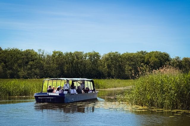 Mensen varen het Naardermeer op in de fluisterboot tussen het riet