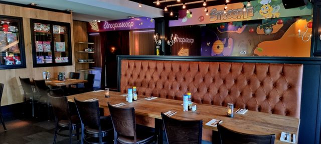 Restaurant De Strooppot in De Hoef, Groene Hart. Sfeervol restaurantinterieur met houten tafels, leren zitbank en de kleurrijke Stroopiescoop voor kinderen.