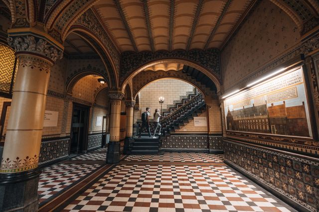 Zwei Personen gehen eine Treppe in einer Halle des alten Gebäudes des Drents Museums in Assen hinauf.