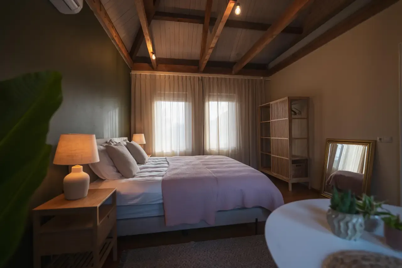 Donkere slaapkamer met groot bed, schemerlampjes en een zitje.