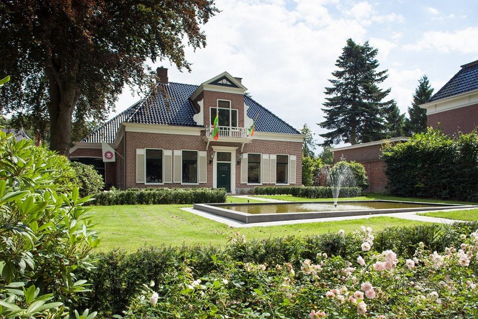 Een karakteristiek huis met een voortuin waarin een fontein staat.