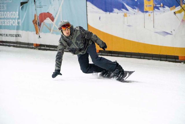Een foto van een man die aan het snowboarden is in SnowWorld.