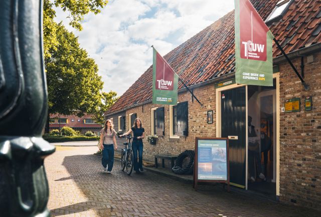 Museum Touwmuseum Oudewater in Oudewater, Groene Hart. Historisch museum over touwslagerij en touwproductie met bezoekers en fiets voor de entree van het karakteristieke monumentale pand in de binnenstad.