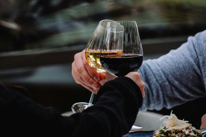 proosten met een glas rode en een glas wiite wijn