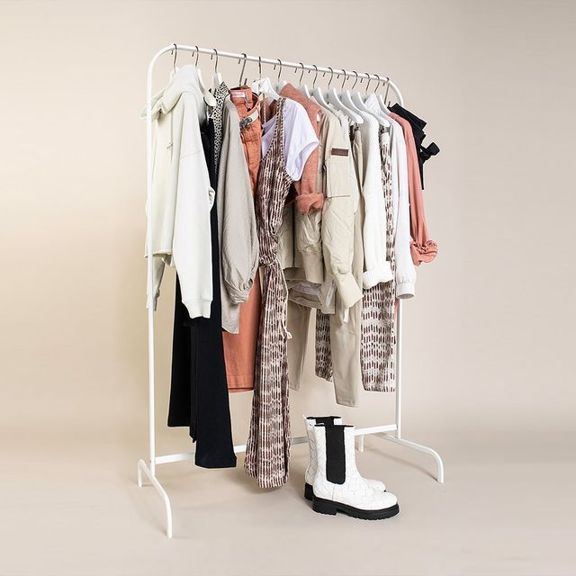 Een kleding rek met verschillende kleding stukken en een paar laarzen