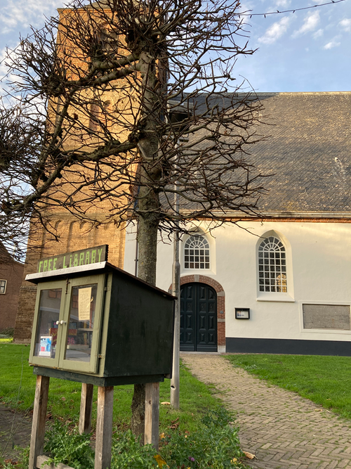 Een kerk met wit gepleisterde muren en een boom ervoor.
