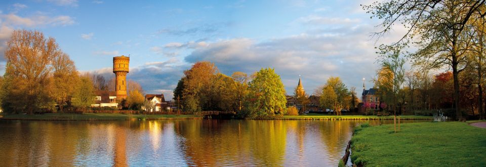 Stadspark Westdampark in Woerden, Groene Hart, met vijver, herfstbomen en de historische watertoren op de achtergrond.