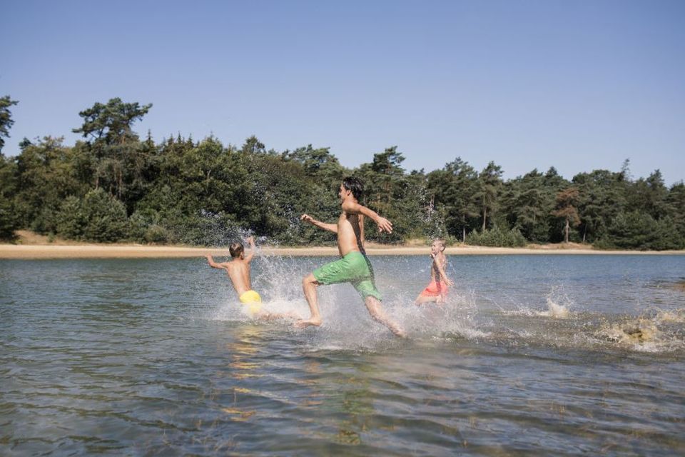 Ein Vater und seine beiden Söhne rennen am Badesee De Kibbelkoele ins Wasser.