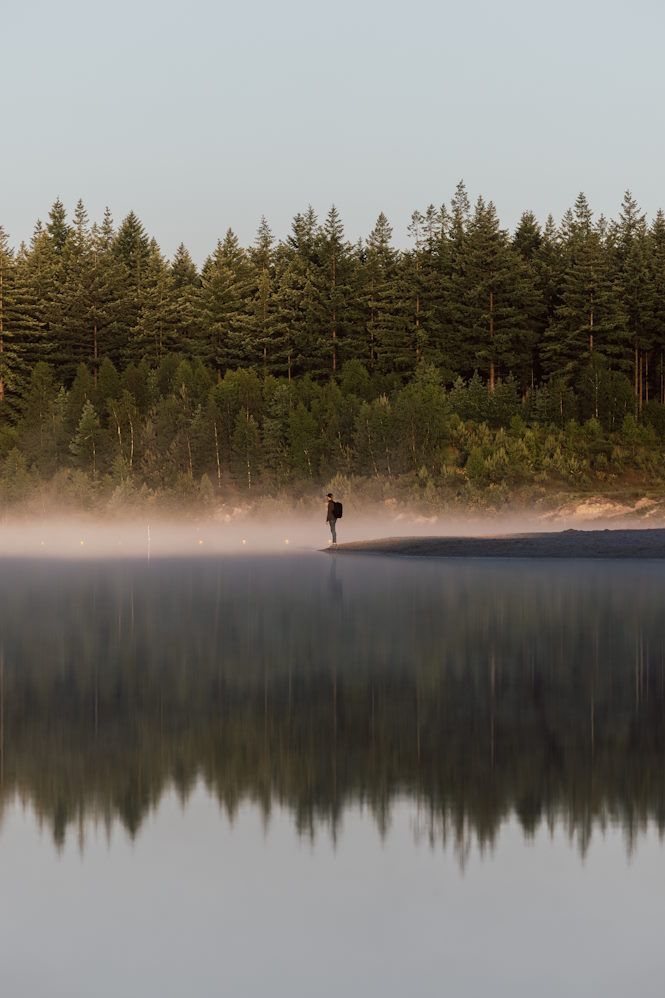 Ein Mann steht im Morgennebel am Ufer des Gasselterveld in Drenthe.