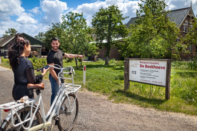 Fietsers arriveren bij biologische boerderij De Beekhoeve in Kamerik, een plek voor boerderijbeleving en streekproducten, onderdeel van Hollandse Ambachten Utrecht Region.
