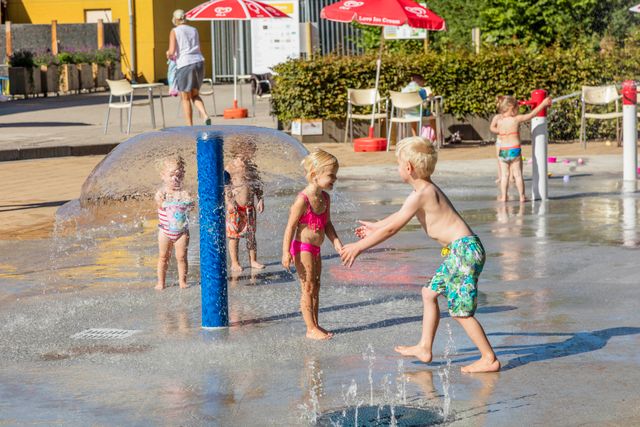 Kinderen spelen met waterstralen en fonteinen bij waterspeeltuin BatensteinBuiten in Woerden op een zonnige dag