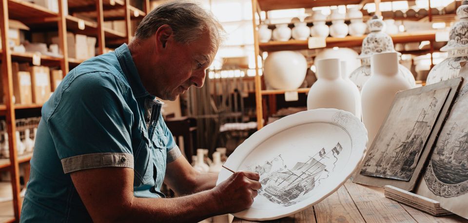 Meesterschilder van Royal Delft aan het schilderen op een bord