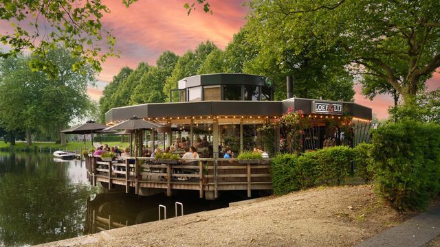 Restaurant Loef & Lij in Woerden, Groene Hart, met sfeervol terras aan het water en gasten aan tafels tijdens zonsondergang. Modern restaurant aan de haven met uitzicht op het stadswater en groene omgeving in de historische vestingstad.