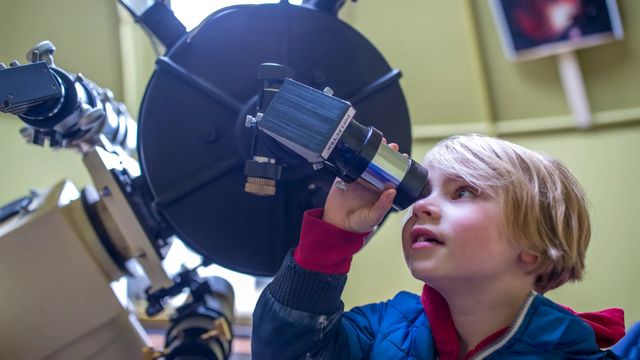 een jongen kijkt door een sterrenkijker