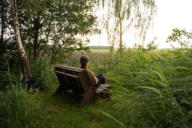 Een vrouw zit op een bankje tijdens een wandeling in de Drentse natuur