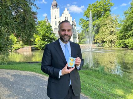 Wethouder Du Maine houdt de opvouwbare plattegrond van Visit Vught in zijn hand.
