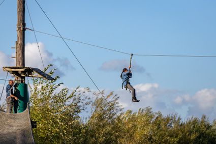 Personen gaan met de zipline vanaf de uitkijktoren bij De Reuselhoeve naar beneden