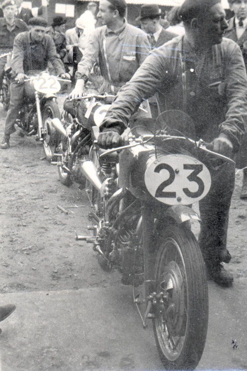 Drie 500cc Moto Guzzi racemotoren worden door fabrieksmonteurs naar de keuring gebracht. Op de voorgrond No. 23 is de machine van Bob Forster, daarachter de Guzzi van Enrico Lorenzetti en achter de machine van Guido Leoni.