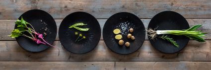 Bovenaf foto van vier zwarte borden op rij gevuld met ieder een ingrediënt