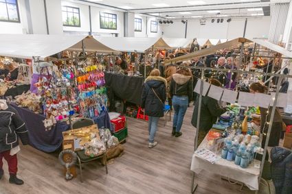 Overdekte kerstmarkt bij WoerdenSport H2O in Harmelen, gemeente Woerden, Groene Hart. Gezellige binnenmarkt met bezoekers, sfeervol verlichte kraampjes, kerstdecoraties, handgemaakte cadeaus en kleurrijke accessoires.