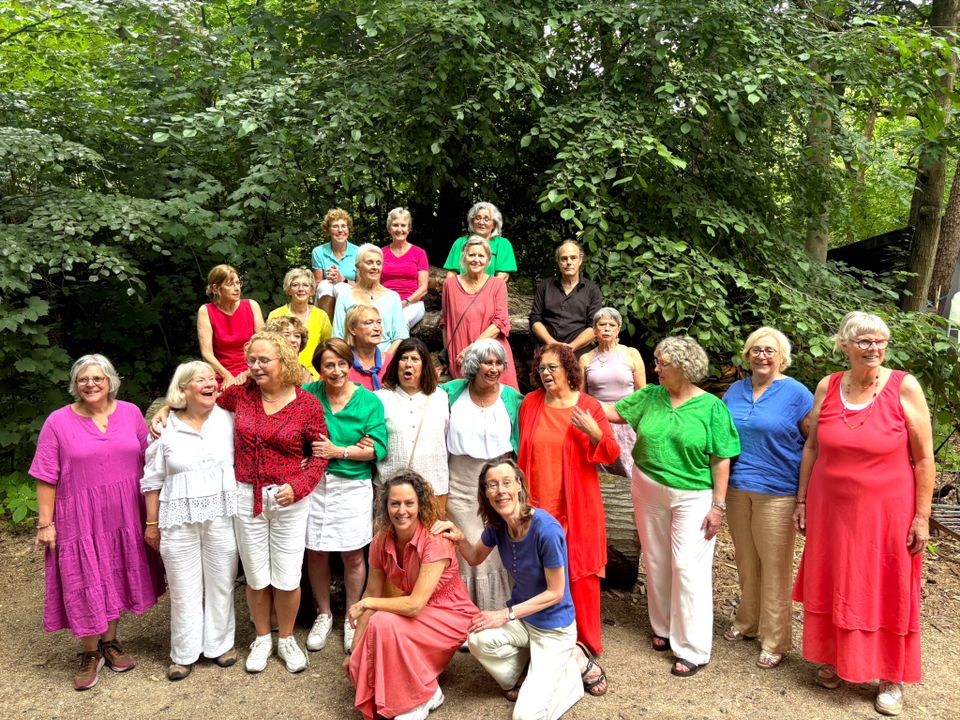 Foto van de leden van Daylight Vocal Group in kleurrijke kleding in een bosrijke omgeving.