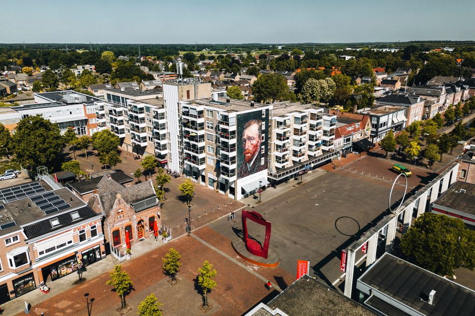 Een drone foto van het centrum van Hoogeveen waarop je goed ziet hoe groot de mural van het hoofd van Vincent van Gogh is aan de zijkant van het appartementencomplex.