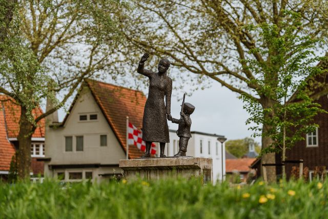 Standbeeld van een moeder en kind die zwaaien.