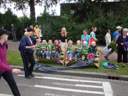 Jeugdige supporters tijdens de eerste dag van de 96e Vierdaagse. Sommige deelnemers met Amerikaanse vlaggetjes (USA) gaan achterlangs. De dame links groet; zij loopt de afstand van 40 km (wit polsbandje).