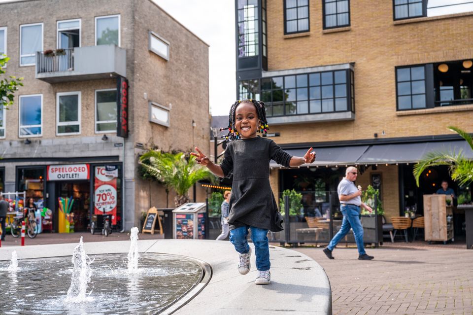 Kind speelt bij waterfontein in het centrum van Oss
