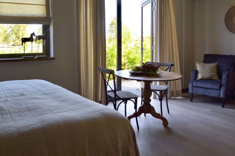 Sfeervolle kamer van B&B Bedje in de Polder in Montfoort, met een comfortabel bed, een kleine eettafel en openslaande deuren naar buiten, waar veel daglicht en uitzicht op het groene buitengebied van het Groene Hart binnenvalt.