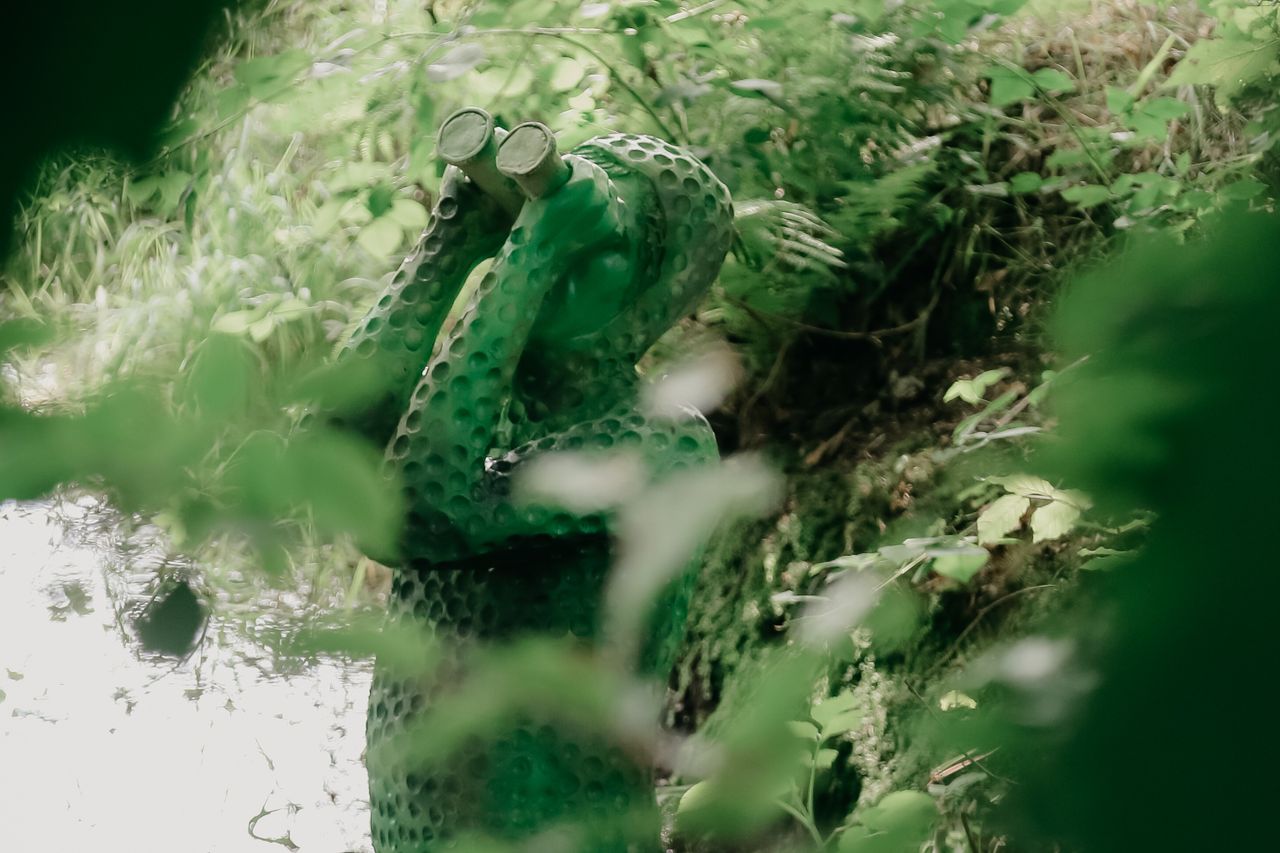 Foto van deel van het kunstwerk Look at me. In het bos bij het beekdal. Groen figuur met verrekijker.