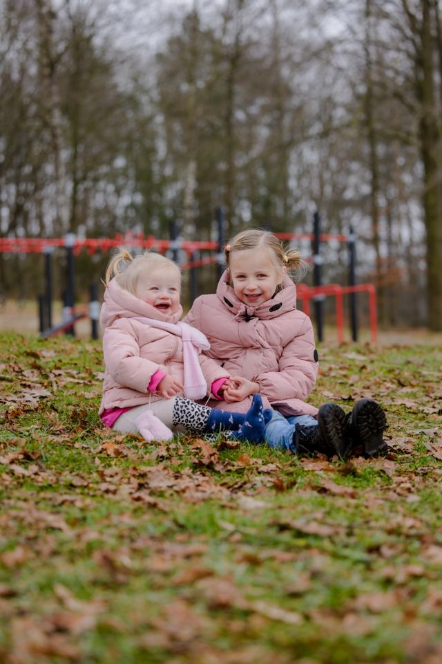 Twee meisjes lachend zittend op de grond