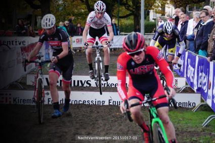 Wielercross tijdens de Nacht van Woerden in Woerden, Groene Hart. Wielrenners springen met hun cyclocrossfietsen over hindernissen op een modderig parcours, terwijl toeschouwers langs de kant de wedstrijd volgen.