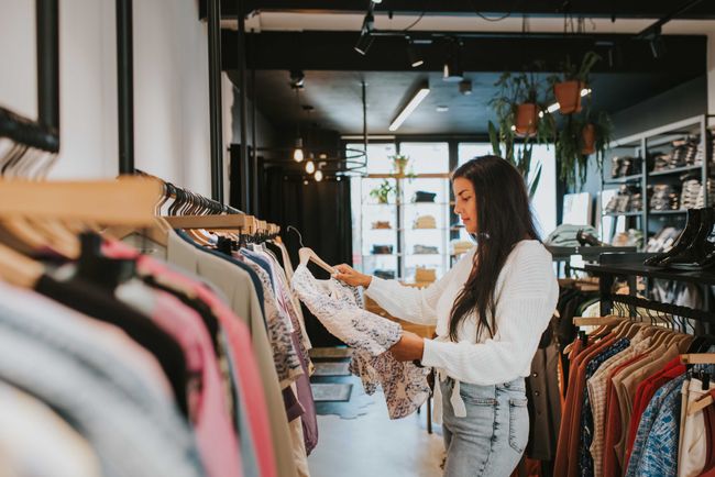Praktische informatie - Koopzondag - Vrouw in een winkel bij kledingrek