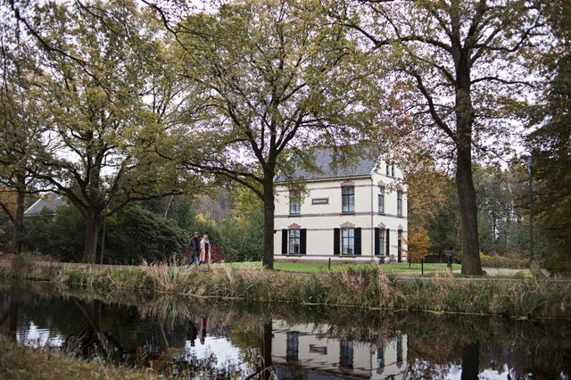 Een stel loopt langs het water in Veenhuizen met op de achtergrond het gebouw Ruimzicht.