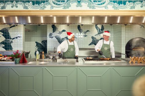 Twee chefs in de keuken aan het koken met een kerstmuts op