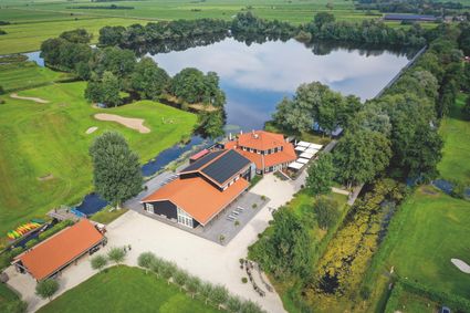 Luchtfoto van Buitenplaats Kameryck te Kamerik aan een plas water met bomen er omheen in een groen gebied met omliggende grasvelden.