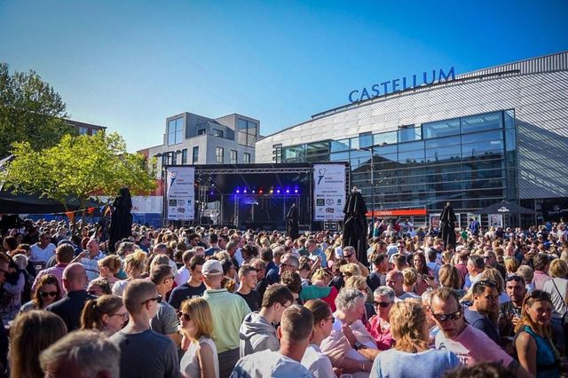 Mensen op het Rijnplein bij het bevrijdingsfestival met op de achtergrond het podium en Castellum.