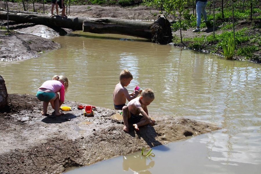 Kinderen spelen met water en modder in de speelweide van Landgoed Bredius in Woerden, natuurlijk buitenspelen in het groen.