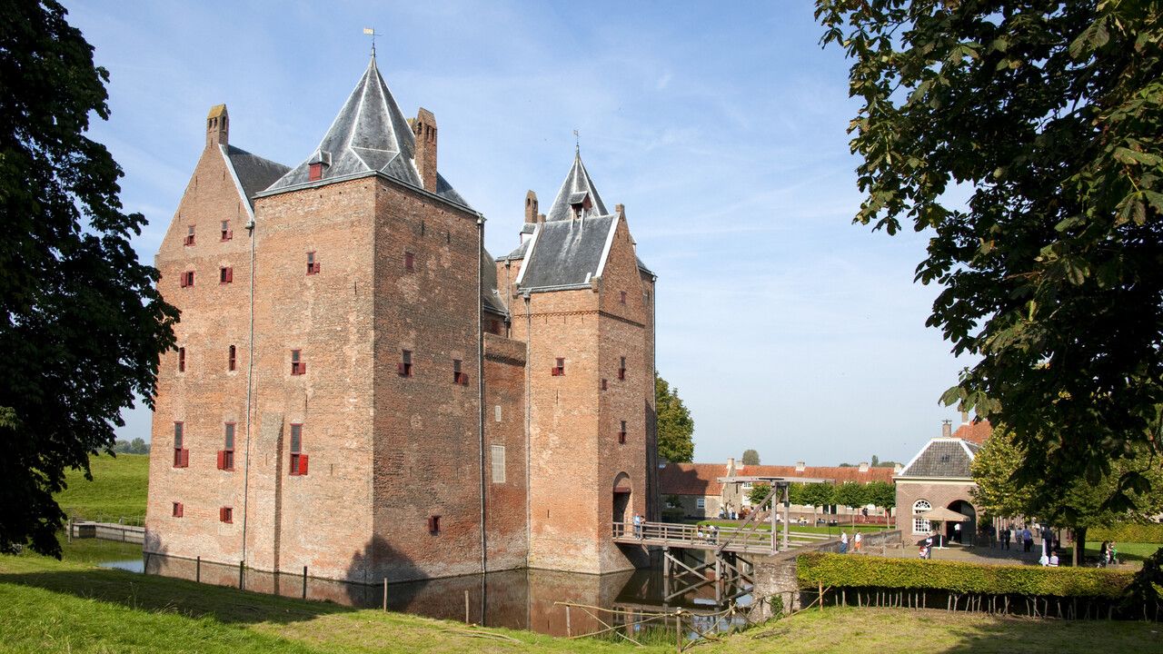 Middeleeuws kasteel Loevestein in Brabant met ophaalbrug en bezoekers op een zonnige dag.