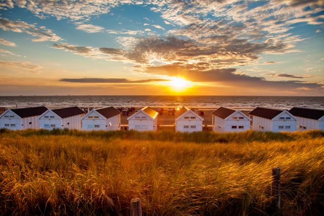 Sfeerbeeld van strandhuisjes in Katwijk aan Zee met ondergaande zon op zee.