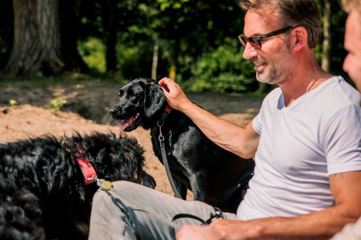 Man zit in het zand met een hond.