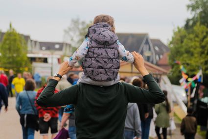 een meisje die op de rug van haar vader zit