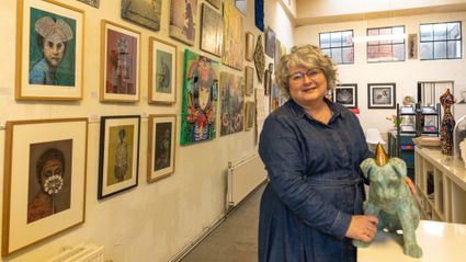 Een sfeervolle blik in Galerie Van Slagmaat in Woerden. Een vrouw staat tussen kleurrijke schilderijen en kunstwerken. De galerie organiseert de expositie PRIDE PROUD PRIMA tijdens de Regenboogweek in Woerden.