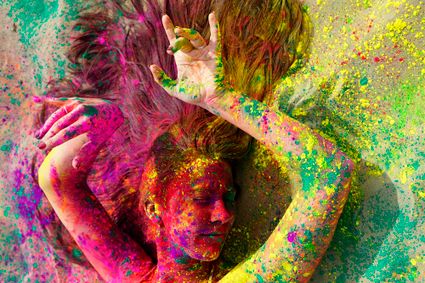 Foto van een vrouw gehuld in allerlei kleuren verfspetters.