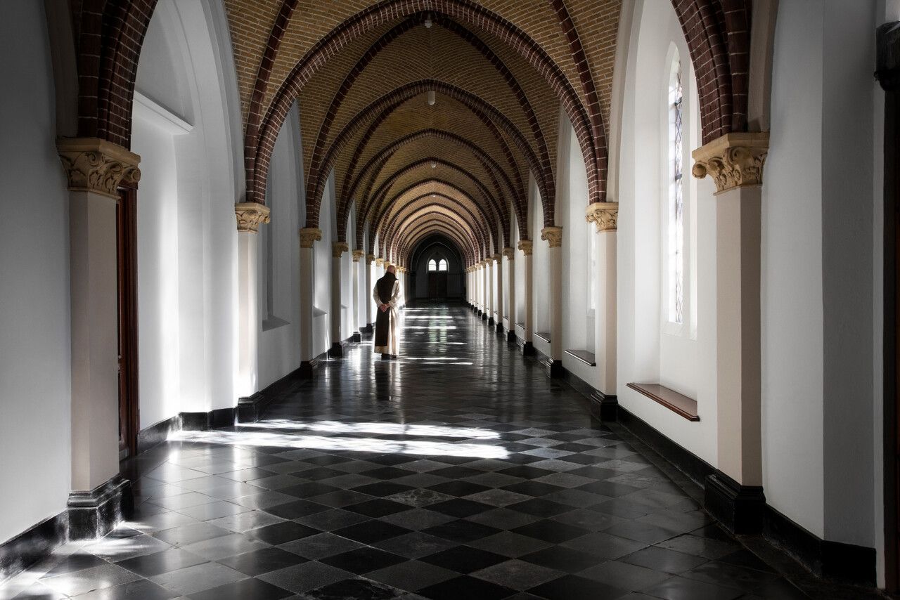 Een monnik die in de hal van de abdij wandelt.