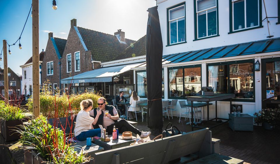 Gasten genieten van een drankje in de zon, op het terras van Proeflokaal De Buuren in Katwijk.