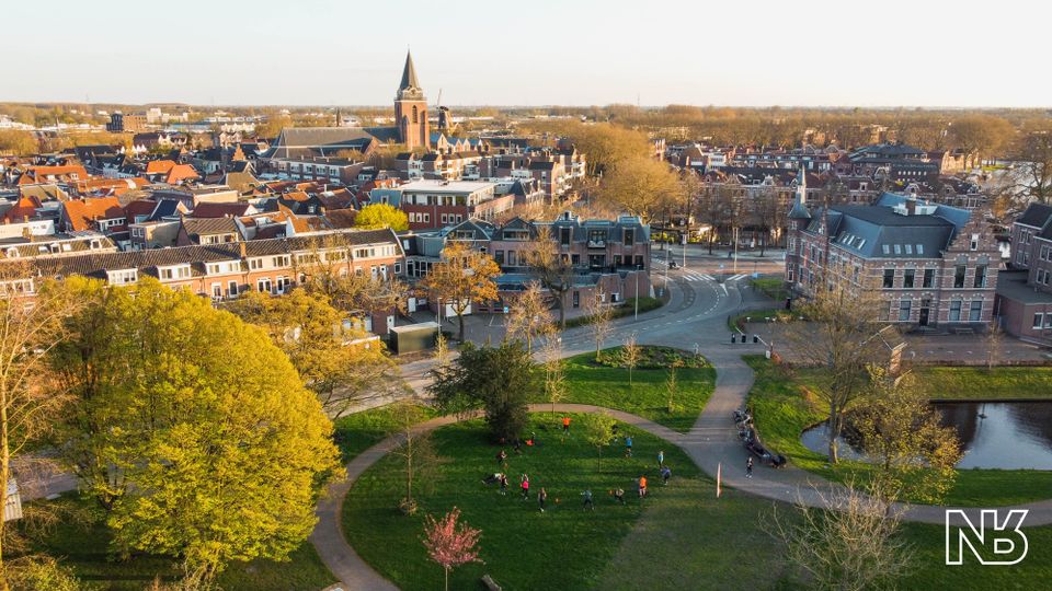 Stadspark Westdampark met sporters, historische binnenstad Woerden, Groene Hart. Luchtfoto met sportende mensen in het park, wandelpaden, veel groen en uitzicht op de Petruskerk en de karakteristieke binnenstad.