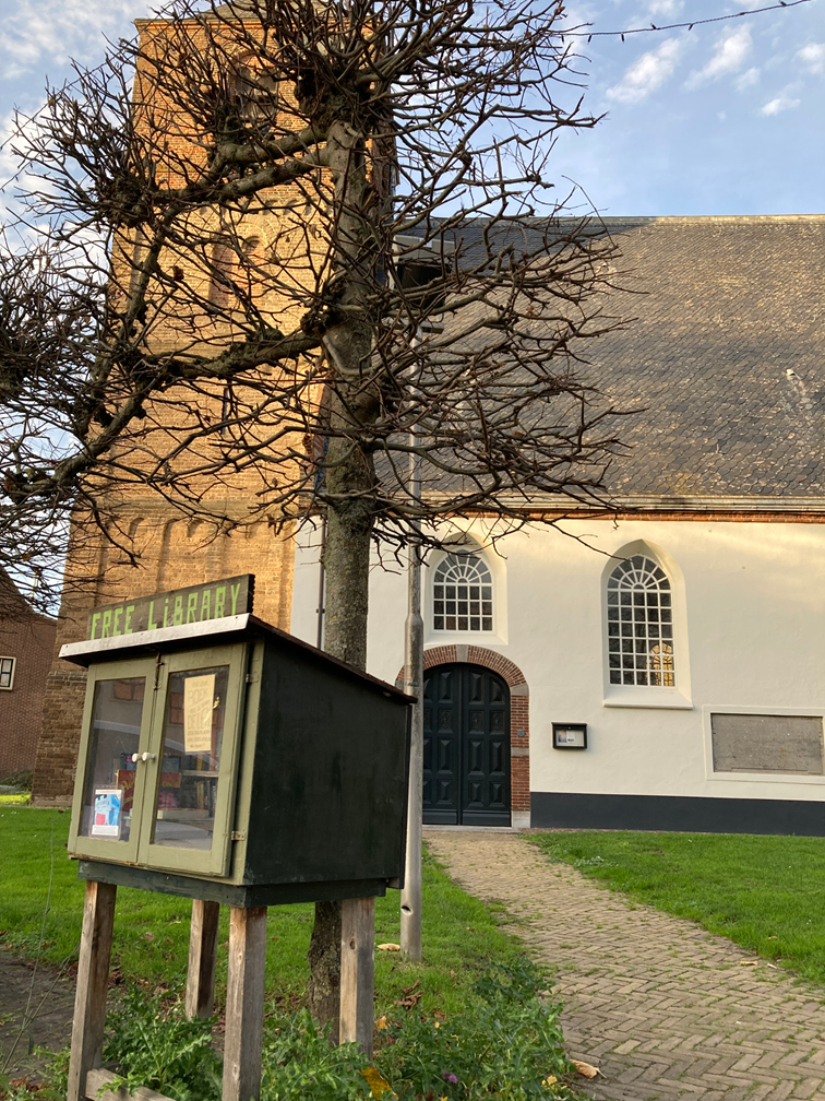 Een kerk met wit gepleisterde muren en een boom ervoor.