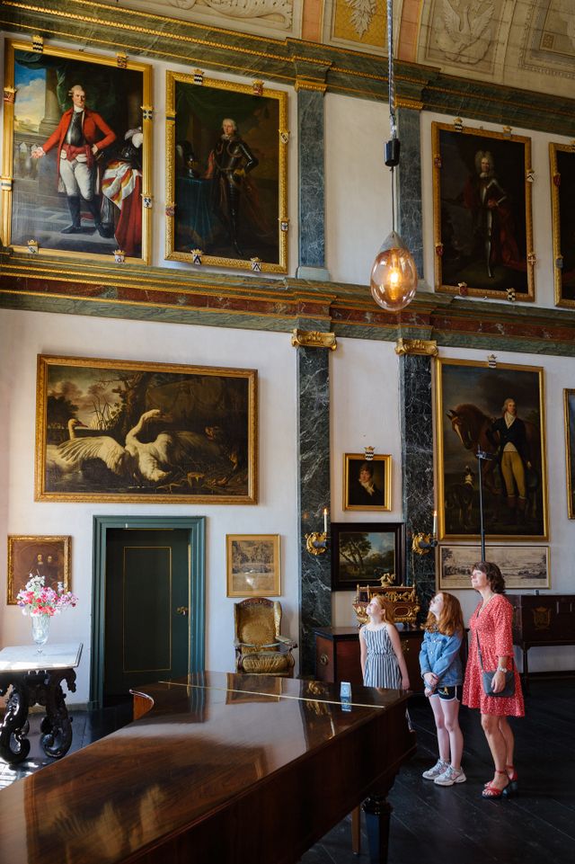 Een gezin bekijkt de schilderijen aan de muren van Kasteel Amerongen
